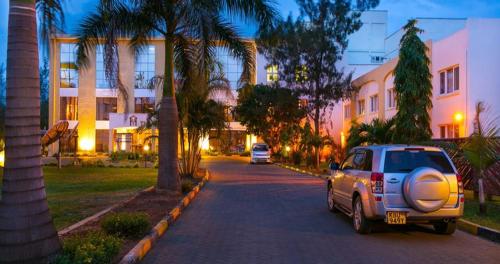 een auto geparkeerd op een straat met palmbomen bij The Vic Hotel in Kisumu