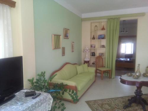a living room with a green couch and a tv at Efstathia Hotel in Xirokambos