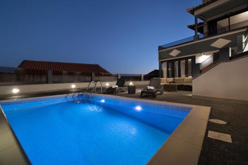 a swimming pool in front of a house at night at ANGEL´S SUNSET in Estreito da Calheta