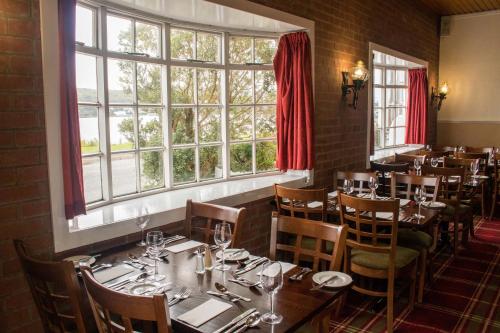 a restaurant with tables and chairs and a large window at Kings Arms Hotel - A Bespoke Hotel in Kyleakin
