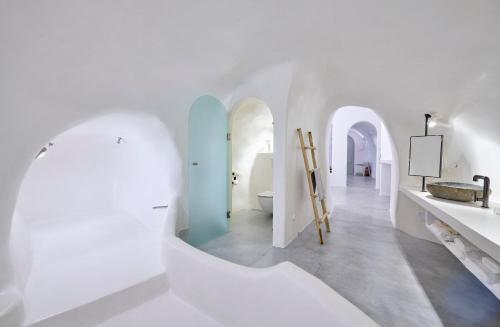 a white bathroom with white walls and a sink at Cave Suite Oia in Oia
