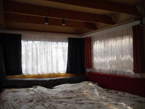 an unmade bed in a bedroom with windows at Ferienwohnwagen Rudolf in Coswig
