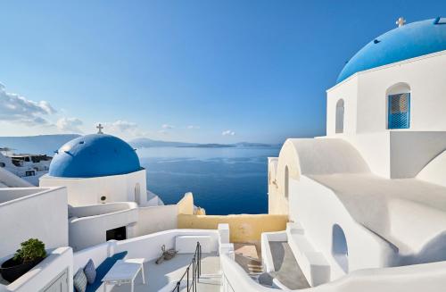 a view of the ocean from the side of a building with blue domes at Cave Suite Oia in Oia