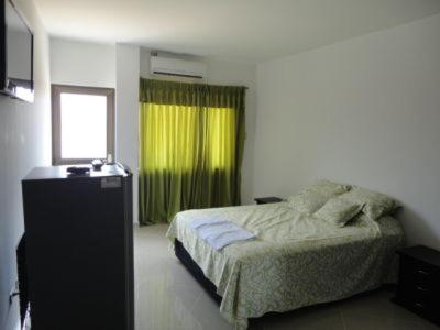 a bedroom with a bed and a green window at Hotel Los Paisas in Mitú