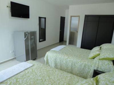 a hotel room with two beds and a flat screen tv at Hotel Los Paisas in Mitú