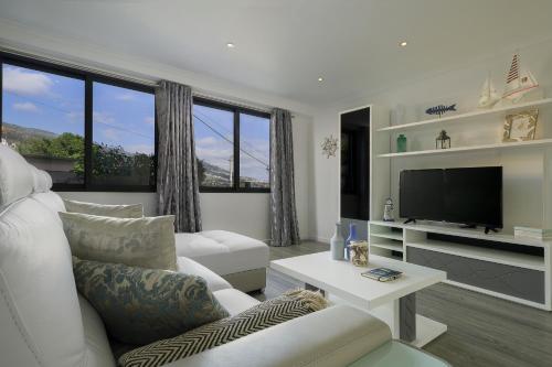 a living room with a white couch and a tv at ANGEL´S SUNSET in Estreito da Calheta