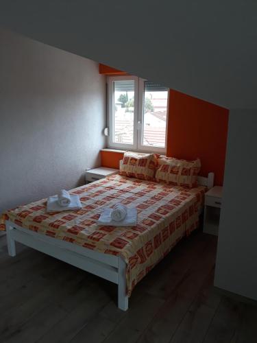 a bedroom with a bed with orange walls and a window at Vila & Apartments MATEA in Gevgelija