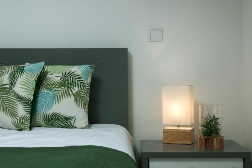 Cama con almohada y mesita de noche con lámpara en ANGEL´S SUNSET, en Estreito da Calheta