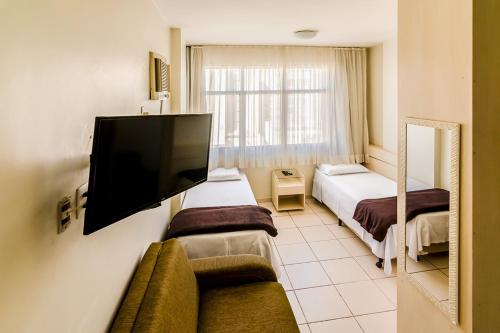 um quarto de hotel com duas camas e uma televisão de ecrã plano em Villa Neves Residence em Belo Horizonte
