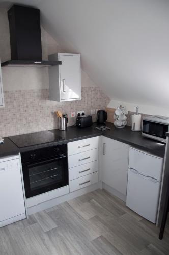 a kitchen with white cabinets and a black appliance at The Square Guest Apartment in Stewartstown