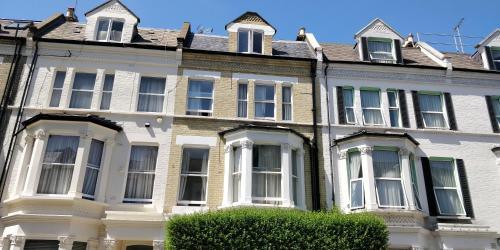 una gran casa blanca con ventanas y un seto en Matheson Olympia Hotel, en Londres