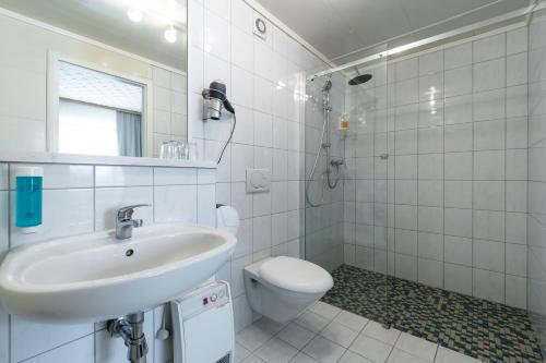 a white bathroom with a sink and a toilet at Hotel Mettlacher Hof in Mettlach