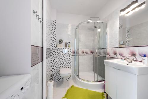 a white bathroom with a shower and a sink at Przytulny Apartament przy Teatrze Wielkim in Warsaw