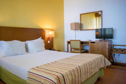 ein Hotelzimmer mit einem großen Bett und einem Schreibtisch in der Unterkunft Bamboo Xaguate Hotel in São Filipe