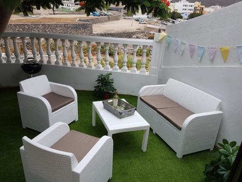 eine Terrasse mit 2 Stühlen, einem Tisch und einem Zaun in der Unterkunft Apartamento Adeje II in Adeje