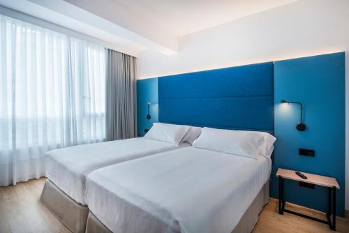 two beds in a hotel room with blue walls at Occidental Vigo in Vigo