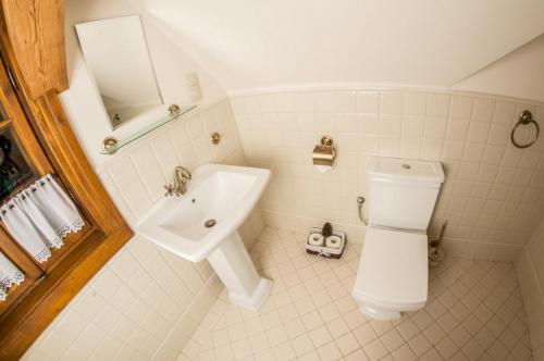 a white bathroom with a sink and a toilet at Pensjonat Dom Zegarmistrza in Bogatynia