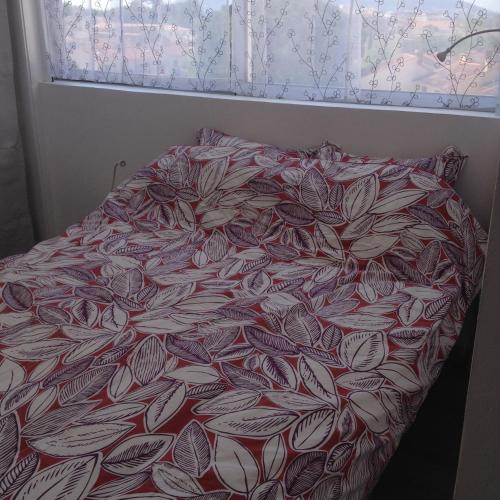 a bed with a red and white comforter and a window at Studio Hesperides in Balaruc-les-Bains