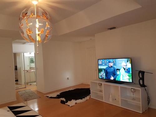 a living room with a flat screen tv and a chandelier at Master Luxury Room in Sunrise