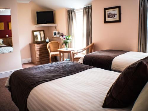 um quarto de hotel com duas camas e uma mesa em Glen Mona em Douglas