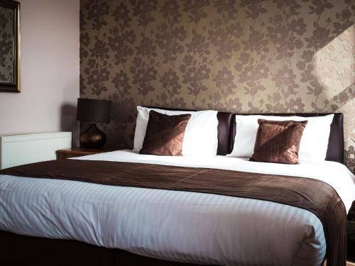 a bedroom with a large bed with brown and white pillows at Rosslyn in Douglas