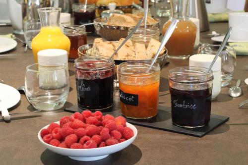 une table recouverte de pots de confiture et d'un bol de fraises dans l'établissement Le clos des pierres rouges, à Saint-Privat-dʼAllier
