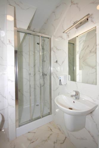a white bathroom with a shower and a sink at Willa Park Apartamenty in Olsztyn