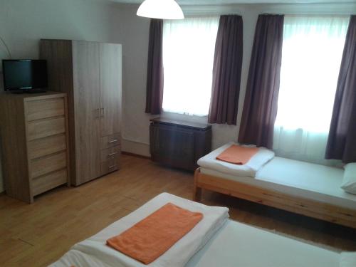 a room with two beds and a tv and windows at 100 ÉVES NOSZTALGIA APARTMAN in Kiszombor
