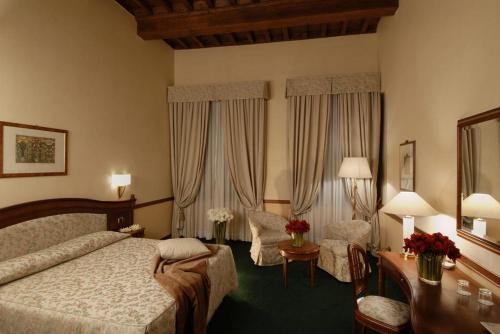 リエーティにあるHotel&Ristorante Miramonti Palazzo Storicoのベッド、デスク、椅子が備わるホテルルームです。