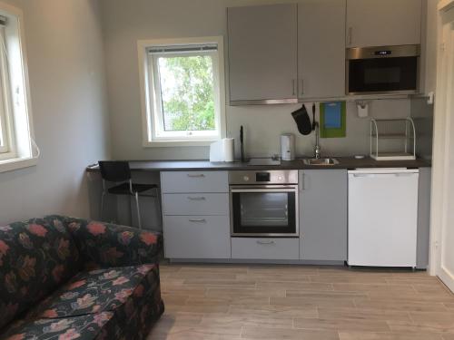 una cocina con electrodomésticos blancos y un sofá en una habitación en Larstorpsvägen 12 en Trollhättan