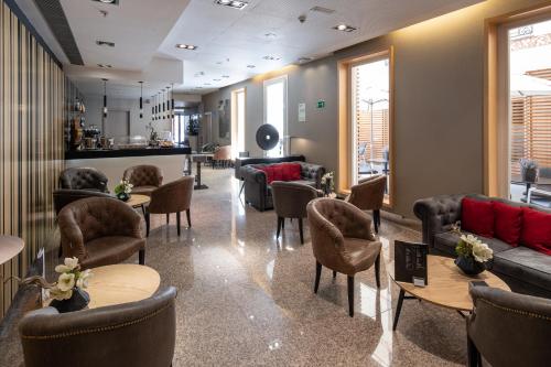 a waiting room with couches and tables and chairs at Catalonia Plaza Mayor in Madrid