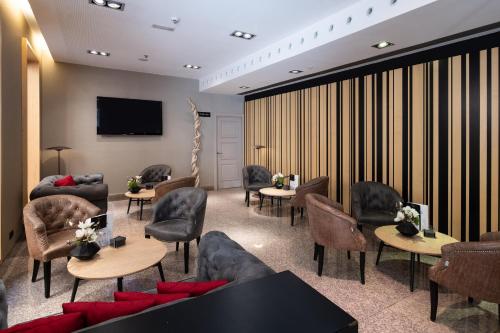a waiting room with chairs and tables and a tv at Catalonia Plaza Mayor in Madrid