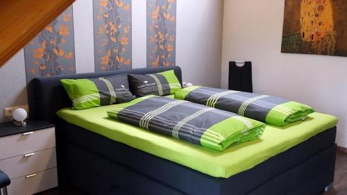 a bed with green and blue pillows on it at Haus Fliegerhorst in Königschaffhausen