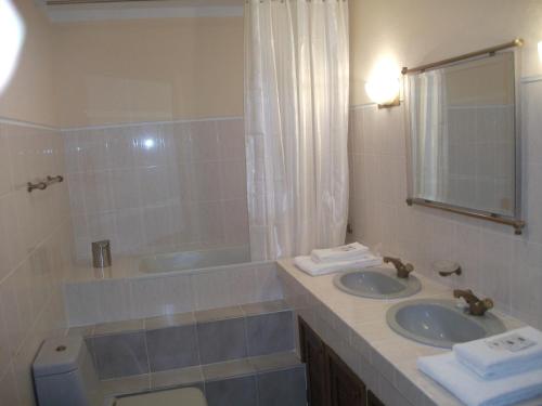 een badkamer met 2 wastafels, een bad en een toilet bij Casa Deus in Sabrosa
