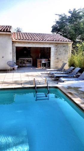 une grande piscine avec des chaises et un patio dans l'établissement Les pondres en vaunage, à Caveirac