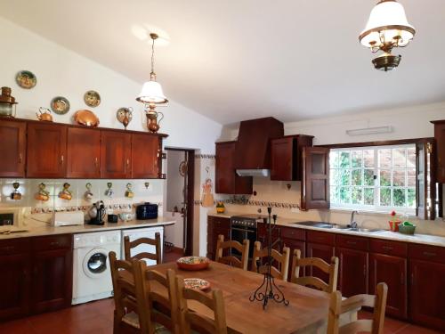 a kitchen with wooden cabinets and a table with chairs at Casa AMOReira de Óbidos in Amoreira