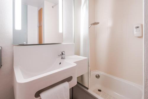 a white bathroom with a sink and a mirror at B&B HOTEL Saint-Nazaire Trignac in Trignac