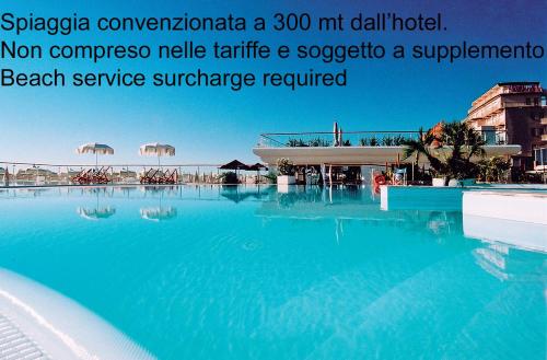 una grande piscina con acqua blu in un resort di Hotel Condor a Milano Marittima