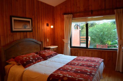 a bedroom with a bed and a large window at Cabañas Entre Verdes in Frutillar