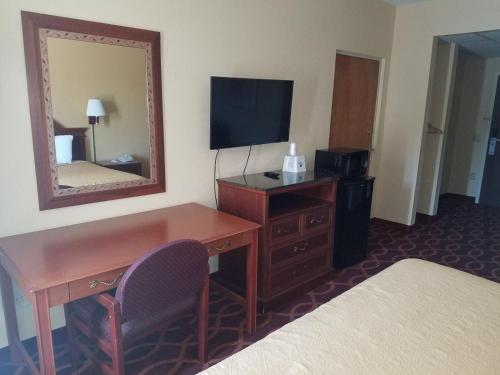 a hotel room with a desk and a mirror at American Inn Evansville East in Evansville