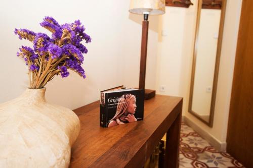 a vase with purple flowers and a book on a table at Residencial Terra de Mar Calpe, Grupo Terra de Mar, alojamientos con encanto in Calpe