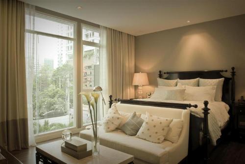 バンコクにあるRongratana Executive Residence Bangkokのベッドとソファと窓のある寝室