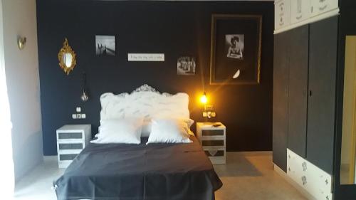 a bedroom with a bed with black walls and white pillows at Villa los Angeles Piscine privée 16 pers in Sant Mateu