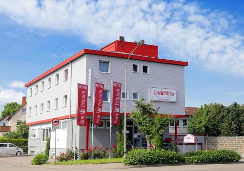 un bâtiment blanc avec des panneaux rouges sur son côté dans l'établissement Hotel Zum Prinzen Sinsheim, à Sinsheim