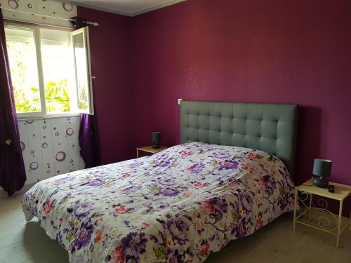 um quarto com uma cama numa parede roxa em 19 Rue du Cadran em Montmorillon