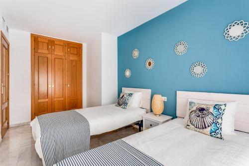 - une chambre avec 2 lits et un mur bleu dans l'établissement Soho Riverside Suite Málaga, à Malaga