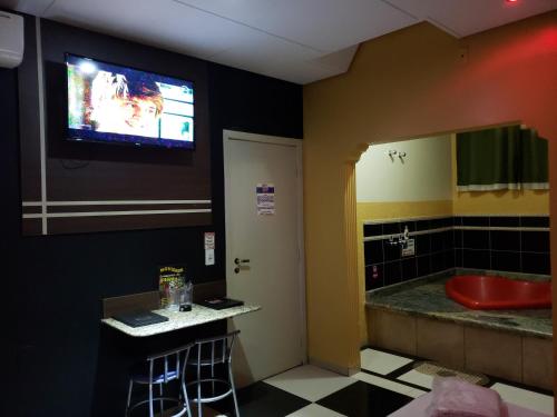 baño con TV en la pared y lavamanos en SP Hotel & Motel, en Mogi Mirim