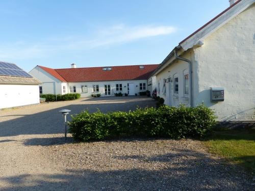 a row of white buildings with red roofs at Sysselbjerg Bed & Breakfast in Almind