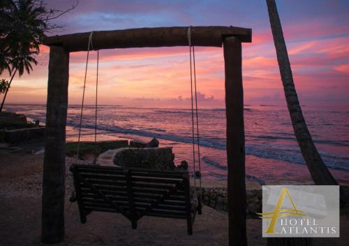 a swing on the beach with a sunset in the background at Hotel Atlantis in Las Terrenas