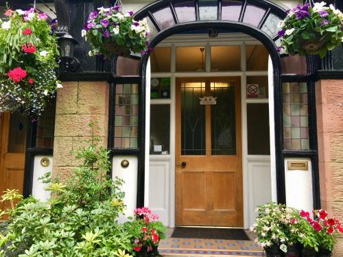an arched entry door to a house with flowers at Ivy Bank Guest House - Room Only in Windermere